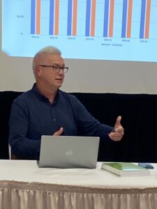 Man sitting in front of a screen, presenting.