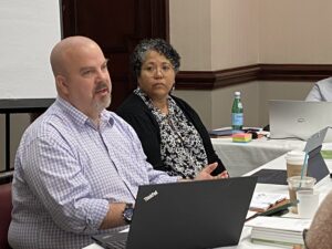 Man and woman sitting in front of a computer presenting.